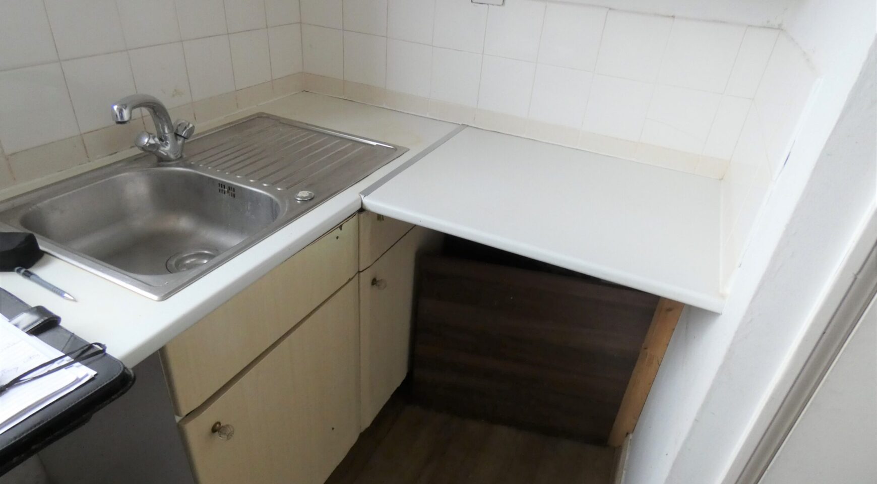 A kitchen with sink, wooden cabinets and white worktops